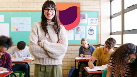 Smiling teacher standing in front of students working in classroom